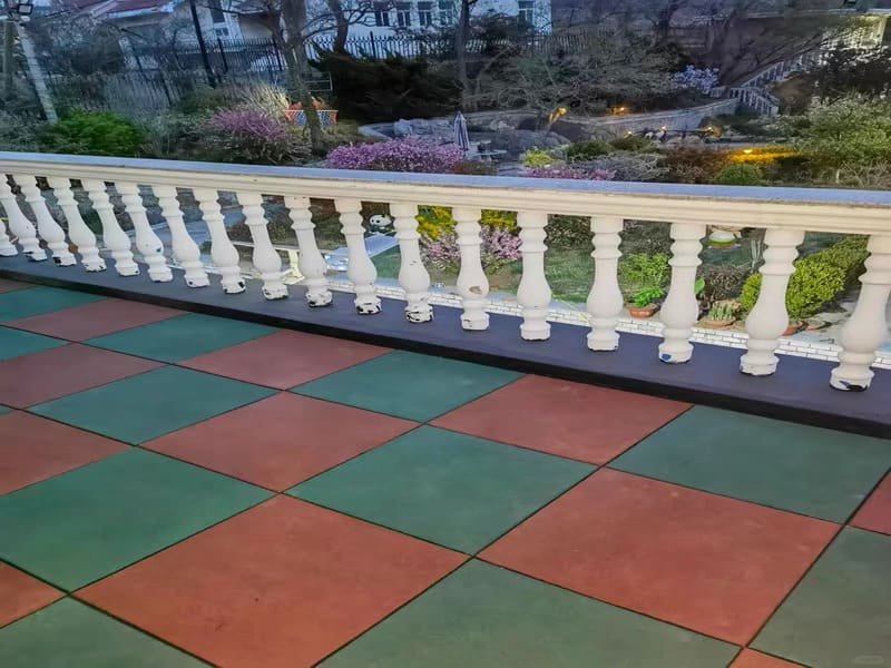 person cleaning rubber tiles with a hose